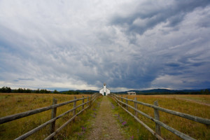 Small white country church with fence and stormy clouds, Alberta, Canada