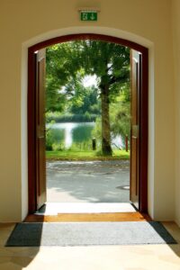 An offer of help opens doors. Pictured: A wood door opened to a view of a garden path.
