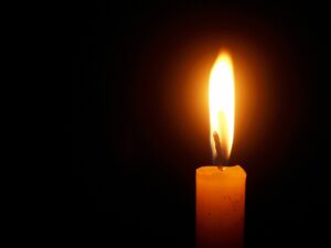 Pictured a single candle flame against a dark background.