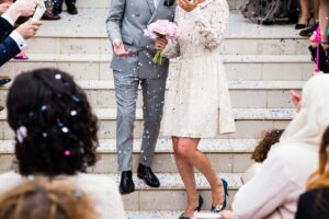 The Reality of Marital Bliss After "I do" blog post by Ken Walker Writer. Pictures a newly married couple coming down a set of stairs among onlookers and confetti.