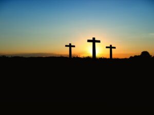 Pictured: Three crosses on a hill silhouetted by a setting sun.