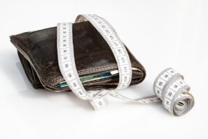 Borrowing Ourselves Into Trouble blog post by Ken Walker Writer. Pictured: A fat wallet with measuring tape aroud it.