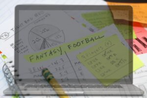 Fantasy League Loses a Bit of Luster blog post by Ken Walker Writer. Pictured a laptop computer interposed over a paper fantasy football draft.