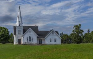 For Better 2025, Go to Church blog post by Ken Walker Writer. Pictured: A large white church sitting out in a field of grass.