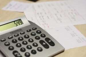 Our Miracle-Working God blog post by Ken Walker Writer. Pictured a calculator sits on a desk and there are budgeting papers in the background.
