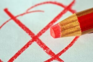 Writers: Get Over Yourself blog post by Ken Walker Writer. Pictured: A red pencil that has written a red "X" and circled it.