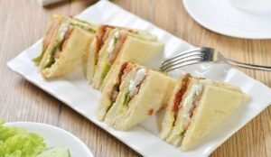 Pictured: A plate with sandwich slices on it. A fork sits nearby.