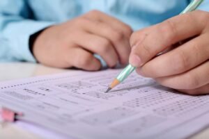 Pictured: A child's hand taking a test on a piece of paper.