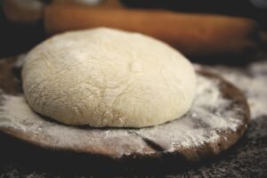 With Books, Haste Makes Waste blog post by Ken Walker Writer. Pictured: A ball of yeast dough sitting on a cutting board to rise.
