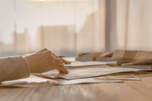 Pictured: A hand on top of a stack of paper as if writing.