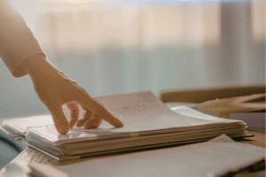 Resting a Key Element of Writing blog post by Ken Walker Writer. Pictured: A hand resting on a pile of papers with the sun streaming in behind.