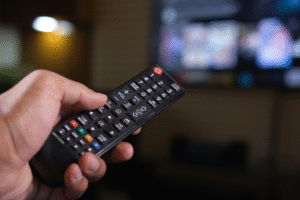 Big Brother is Always Watching blog post by Ken Walker Writer. Pictured: A smart Television in the background and hand holding a remote up close.