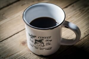 Pictured: A cup of coffee sitting on a wood table.