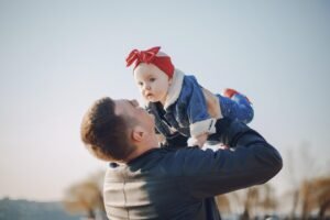 A Father’s Riches blog post by Ken Walker Writer. Pictured: A Father lifting his baby above his head.