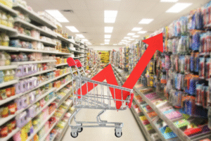 Pictured: A retail store in the background. In the foreground a shopping cart with an arrow pointing up, indicating increasing prices.