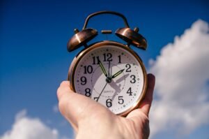 Pictured: A hand holding out an old fashioned clock.