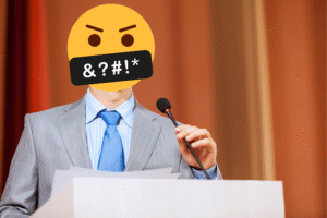 Foul Talk Generates Widespread Damage blog post by Ken Walker Writer. Pictured: A man standing behind a podium giving a speech. His face is covered by a yellow emoji with "&?#!*" as if he was using foul language.