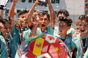 With Sports, Amateurs Rule blog post by Ken Walker Writer. Pictured: A World Cup soccer ball in the foreground. Youth's cheer amid falling confetti in the background.