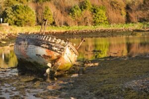 Scheduling Time a Great Writing Habit blog post by Ken Walker Writer. Pictured: A ship sitting on it's side in the mud near a lake.