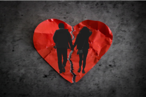 ‘Chasing Rich’ Shows God in Action blog post by Ken Walker Writer. Pictured: A crumpled paper heart that's been torn in two is behind a couple holding hands, signifying divorce.
