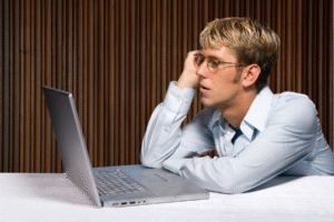 Writers Can’t Try to ‘Get Even’ blog post by Ken Walker Writer. Pictured: A bored man sits at a laptop as if waiting for a response but being ghosted.