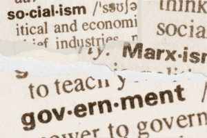 Socialism Can’t be Forced blog post by Ken Walker Writer. Pictured: A torn paper collage with dictionary pages showing socialism, Marxism, and government.